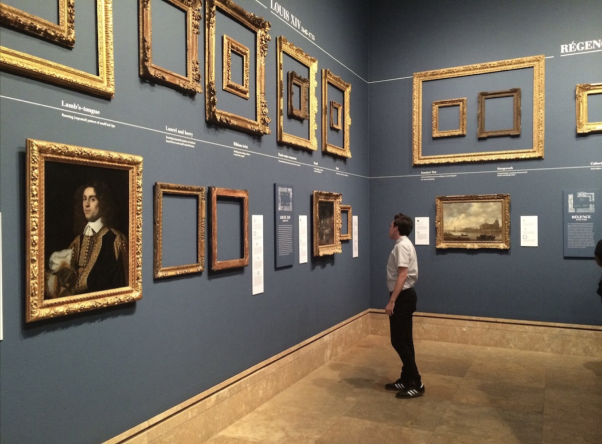 Museum exhibition wall showing Louis XIV era frames on blue background