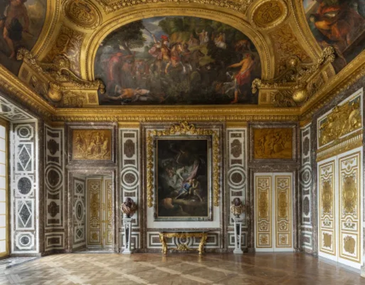 Grand salon at the Palace of Versailles lined with baroque gold-framed paintings